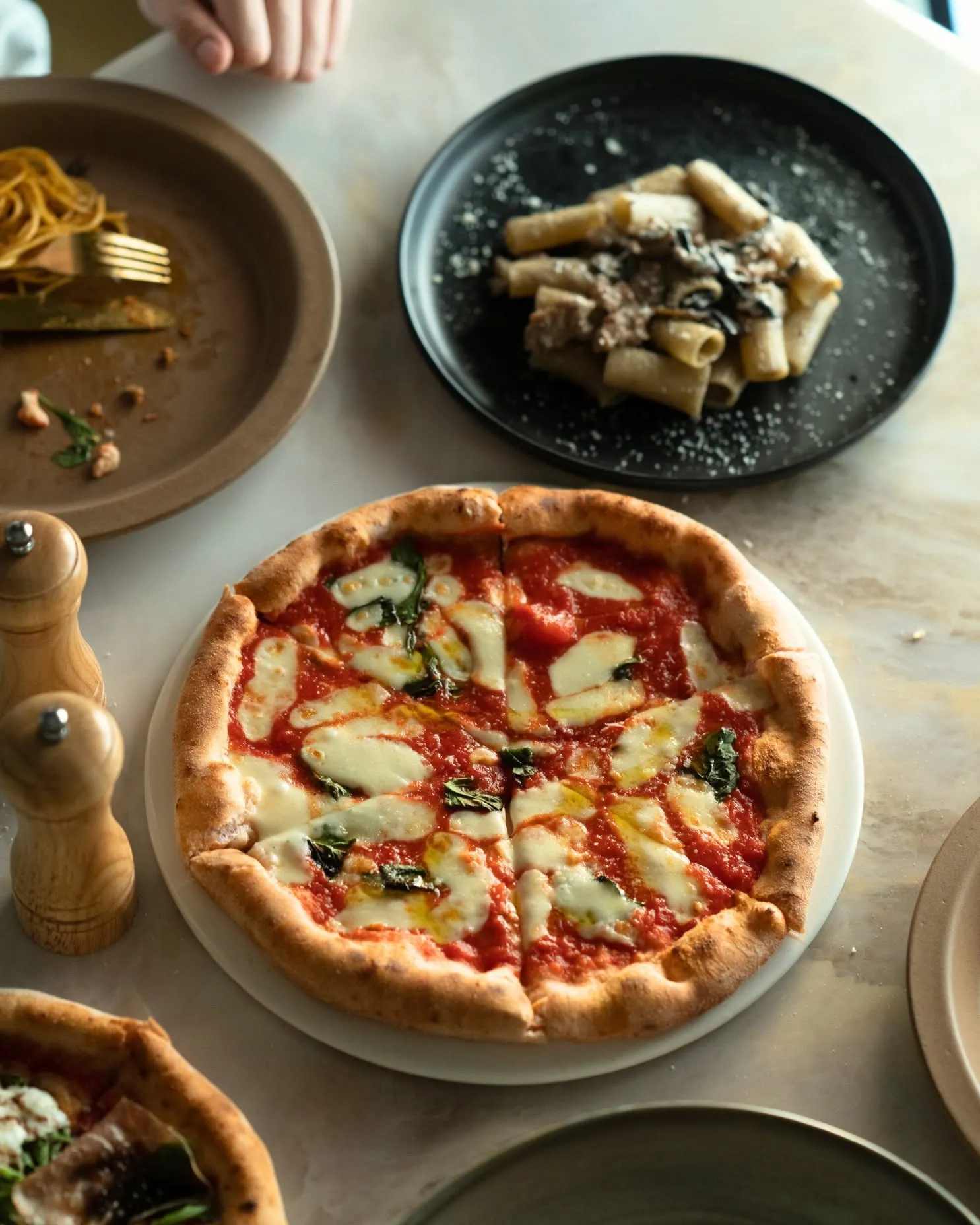 A marble table in daylight set with the Queen Margherita and pasta
