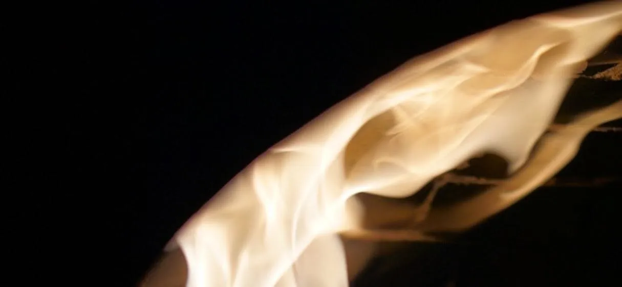 A tongue of flame arcing across the mouth of the wood-fired oven