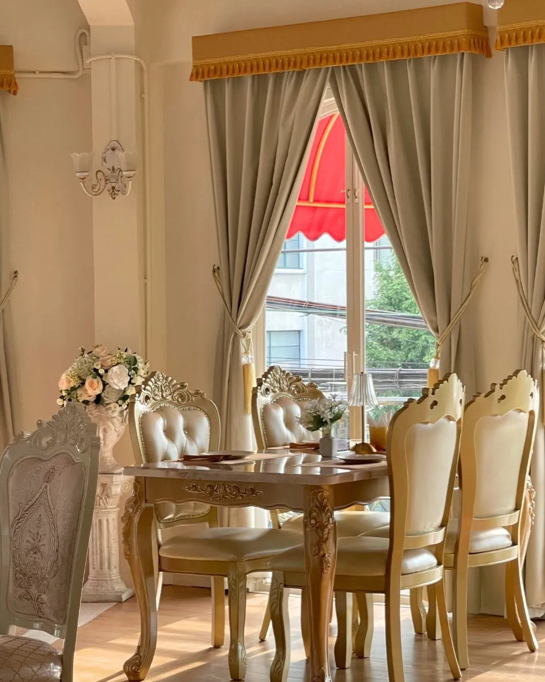 The dining room in afternoon light, cream and gold chairs by the window